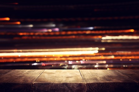 Image of wooden table in front of abstract blurred restaurant lights backgroundの写真素材