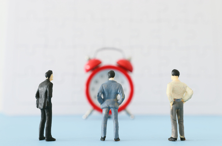 Concept image of miniature people looking at alarm clock. Deadline and teamworkの写真素材