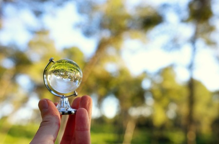 Small crystal globe in front of sunset. Travel and global issues conceptの写真素材