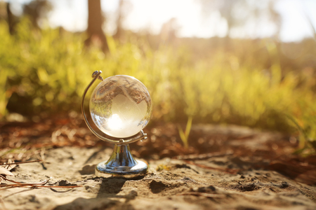 Small crystal globe in front of sunset. Travel and global issues conceptの写真素材