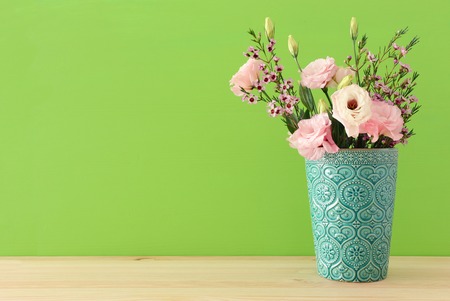 spring bouquet of pastel and delicate pink flowers in the vase over wooden tableの写真素材