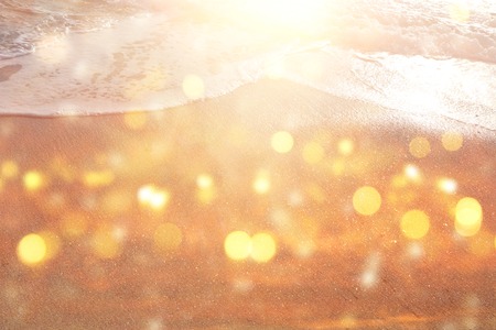 Background image of sandy beach and ocean waves with bright bokeh lightsの写真素材