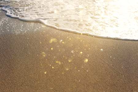 Background image of sandy beach and ocean waves with bright bokeh lightsの写真素材