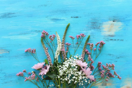 Spring bouquet of pink and white flowers over blue vintage wooden background. Top view, flat layの写真素材
