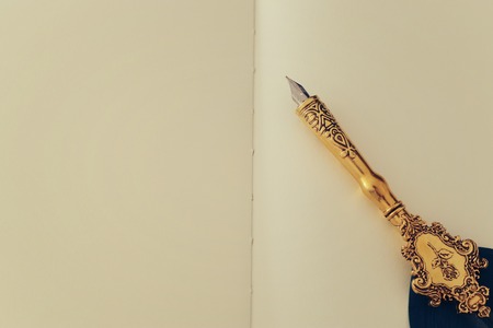 Old feather pen and empty sheet of paper. Back drop background. View from above.