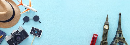 Top view banner photo of traveling concept with accessories and world symbols over blue background