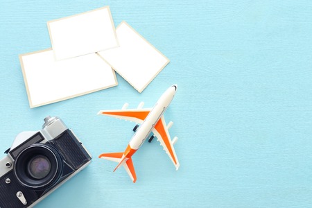Top view of empty photographs frame next to airplane and camera over wooden table. Traveling concept. Ready to mock upの写真素材