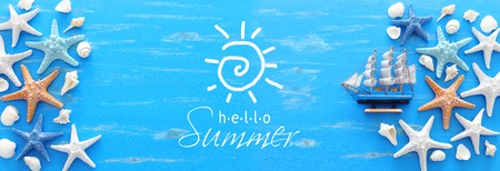 vacation and summer concept with starfish, seashells and boat over blue wooden background. Top view flat layの写真素材