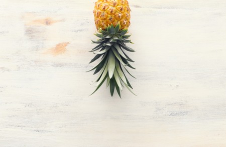 Ripe pineapple over white wooden background. Beach and tropical theme. Top view