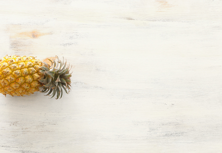 Ripe pineapple over white wooden background. Beach and tropical theme. Top viewの写真素材