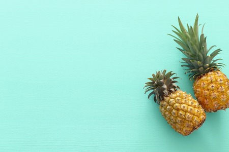 Ripe pineapple over mint wooden background. Beach and tropical theme. Top view