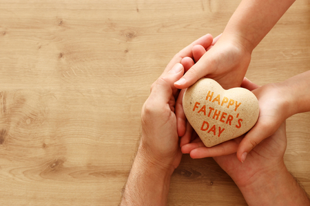 father and little child holding together wooden heart. Happy father's day concept.の写真素材