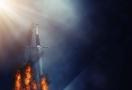 Mysterious and magical photo of silver sword with fire flames over Gothic black background. Medieval period conceptの写真素材