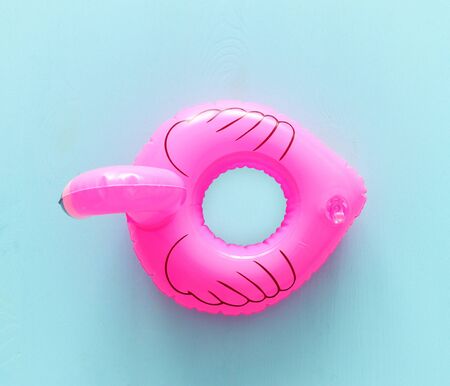 Inflatable pink flamingo ring over blue wooden background