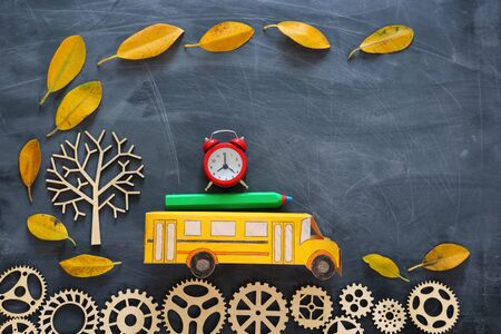 education and back to school concept. Top view photo of cardboard school bus, alarm clock and pencil...