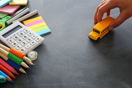 education and back to school concept. stationery and bus over classroom blackboard. top view