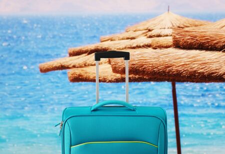 Holidays. Travel concept. Blue suitcase in-front of tropical backgroundの写真素材