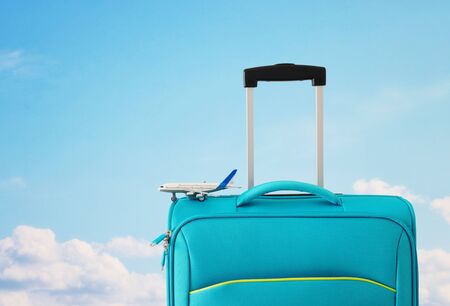 Holidays. Travel concept. Blue suitcase and airplane toy in-front of sky backgroundの写真素材