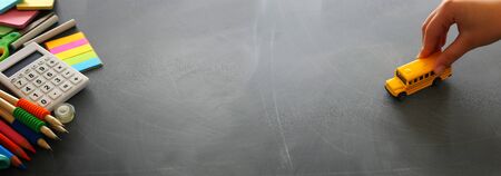 education and back to school concept. stationery and bus over classroom blackboard. top view