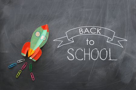 Education. Back to school concept. Rocket cut from paper and painted over blackboard background. Top...
