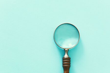 Vintage magnifying glass with wooden handle over blue background. Top view, flat layの写真素材