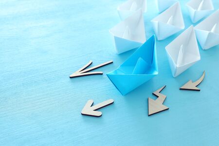 business. Leadership concept image with paper boats on blue wooden background. One leader guiding...