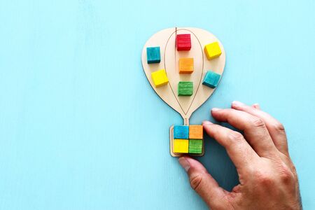 Business image of wooden air balloon with colorful cubes over blue table, human resources and...