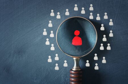 business image of magnifying glass with people icon over chalkboard background, building a strong team, human resources and management conceptの写真素材