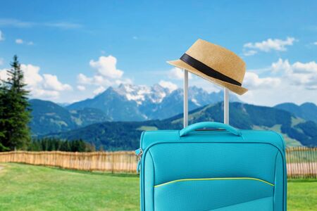 recreation image of traveler luggage and fedora hat in.front of a rural landscape. holiday and vacation conceptの写真素材