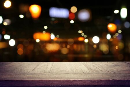 background Image of wooden table in front of abstract blurred restaurant lightsの写真素材
