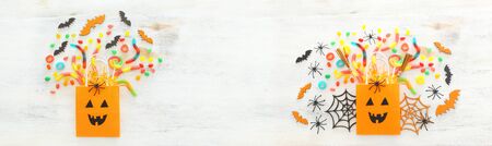 holidays image of Halloween. paper gift bag, spider, bats and sweets over wooden white table. top view, flat layの写真素材