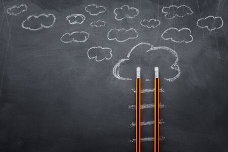 Education concept of Ladder made from pencils next to clouds over blackboardの写真素材