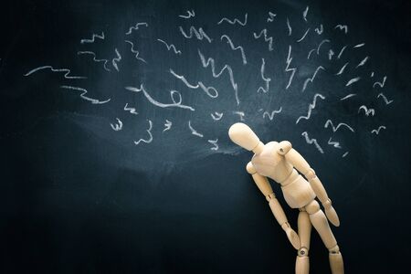image of wooden dummy over blackboard with worried stressed thoughts. depression, obsessive compulsive, adhd, anxiety disorders conceptの写真素材