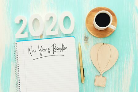 Business concept of top view 2020 year's resolution list with notebook, cup of coffee over pastel...