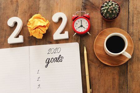 Business concept of top view 2020 goals list with notebook, cup of coffee over wooden deskの写真素材
