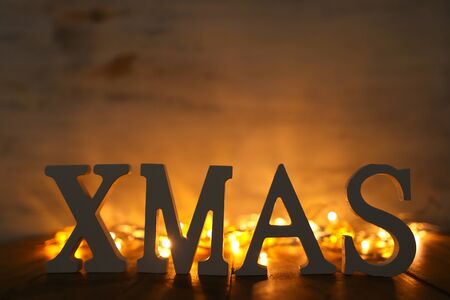 Background of happy new year concept, wooden XMAS letters over table and gold darland lights backgroundの写真素材