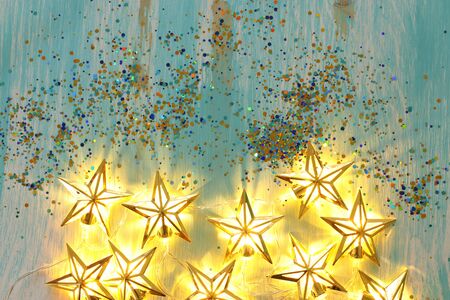 holidays concept of Christmas warm gold garland lights over wooden blue background
