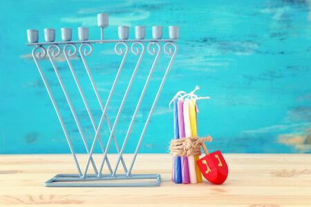religion image of jewish holiday Hanukkah with menorah (traditional candelabra) and spinning top over wooden table and blue backgroundの写真素材