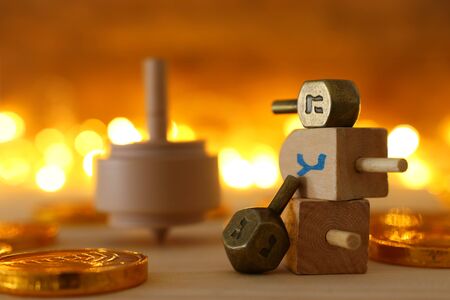 religion concept of of jewish holiday Hanukkah with wooden dreidels (spinning top) and chocolate coins over wooden table and bokeh lights backgroundの写真素材