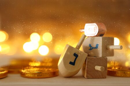 religion concept of of jewish holiday Hanukkah with wooden dreidels (spinning top) and chocolate coins over wooden table and bokeh lights background