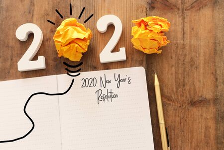Business concept of top view 2020 year's resolution list with notebook over wooden desk