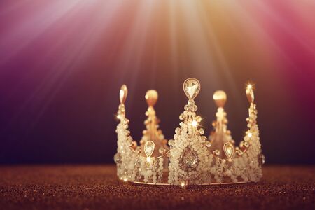 low key image of beautiful queen/king crown over gold glitter table. vintage filtered. fantasy medieval periodの写真素材
