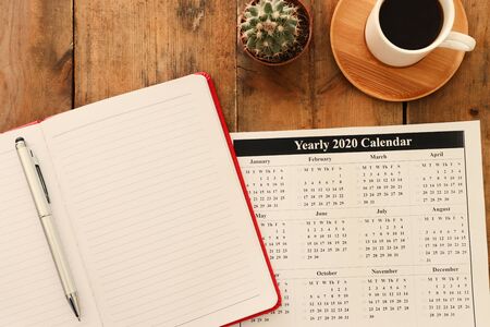Business concept of top view 2020 plan list with notebook, cup of coffee over blue wooden desk