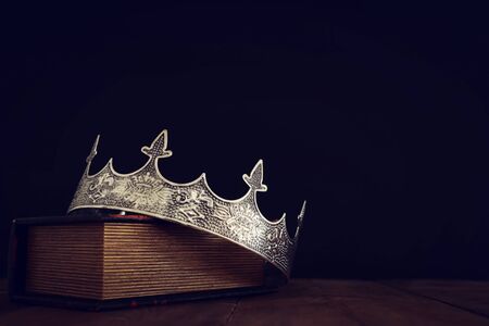 low key image of beautiful queen/king crown over old book and wooden table. vintage filtered. fantasy medieval periodの写真素材