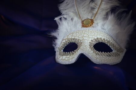 Photo of elegant and delicate white Venetian mask over purple silk backgroundの写真素材