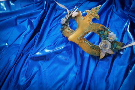 Photo of elegant and delicate Venetian mask over blue silk backgroundの写真素材