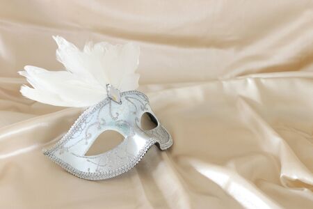 Photo of elegant and delicate white Venetian mask over white silk backgroundの写真素材
