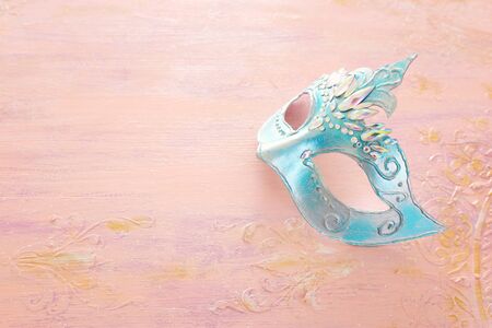 Photo of elegant and delicate blue Venetian mask over pastel wooden background