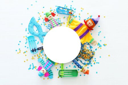 Party colorful noisemaker, mask and cute clown doll over white wooden background . Top view, flat layの写真素材