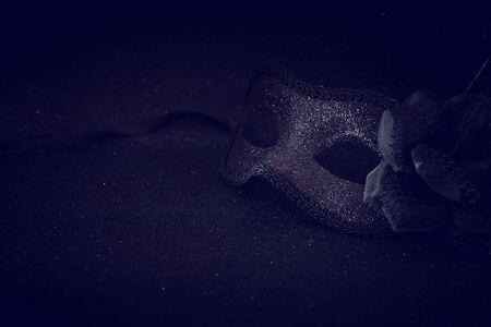 Photo of elegant and delicate black Venetian mask over dark glitter backgroundの写真素材